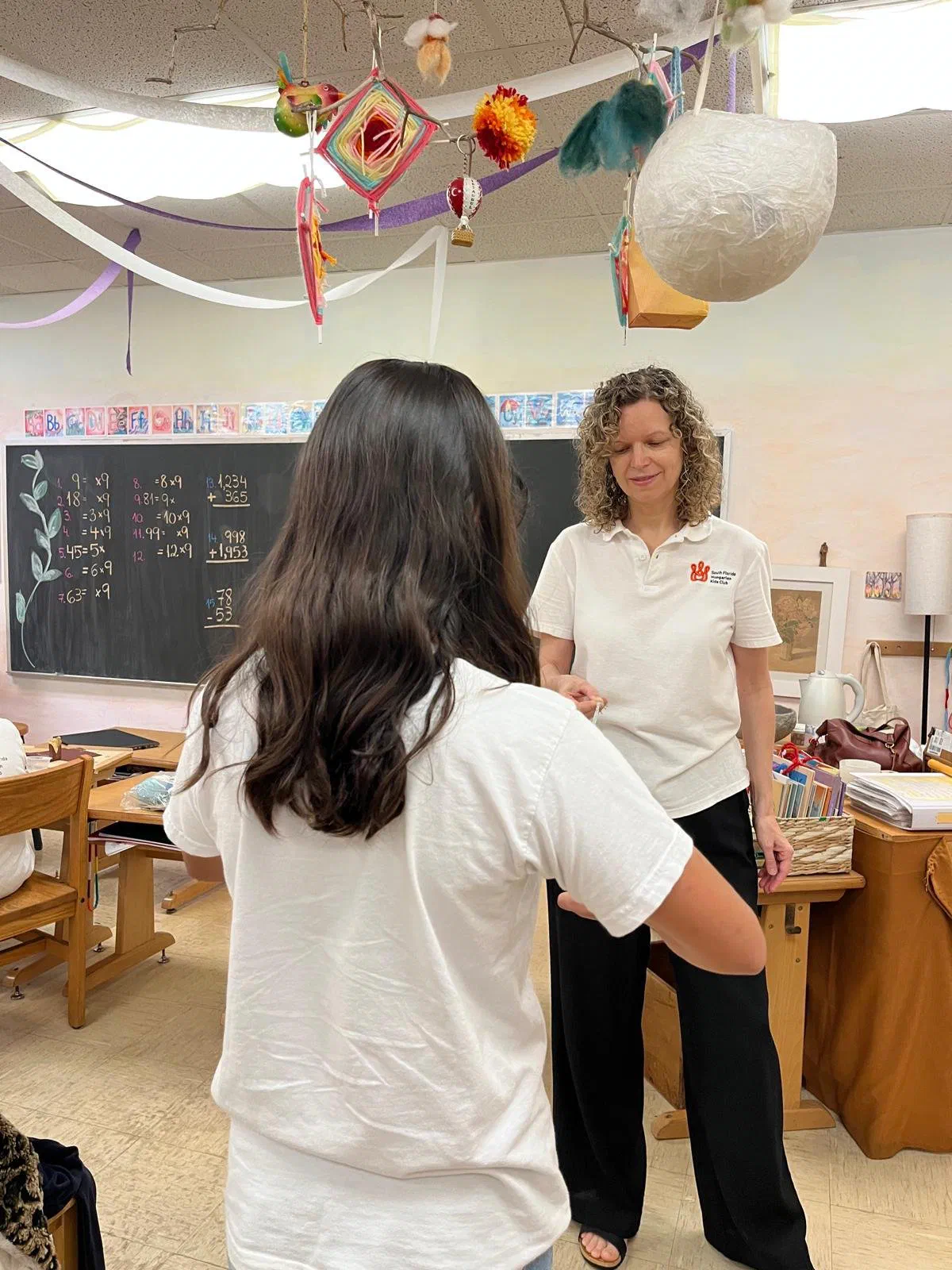 Olga finger weaving with a student in a classroom.